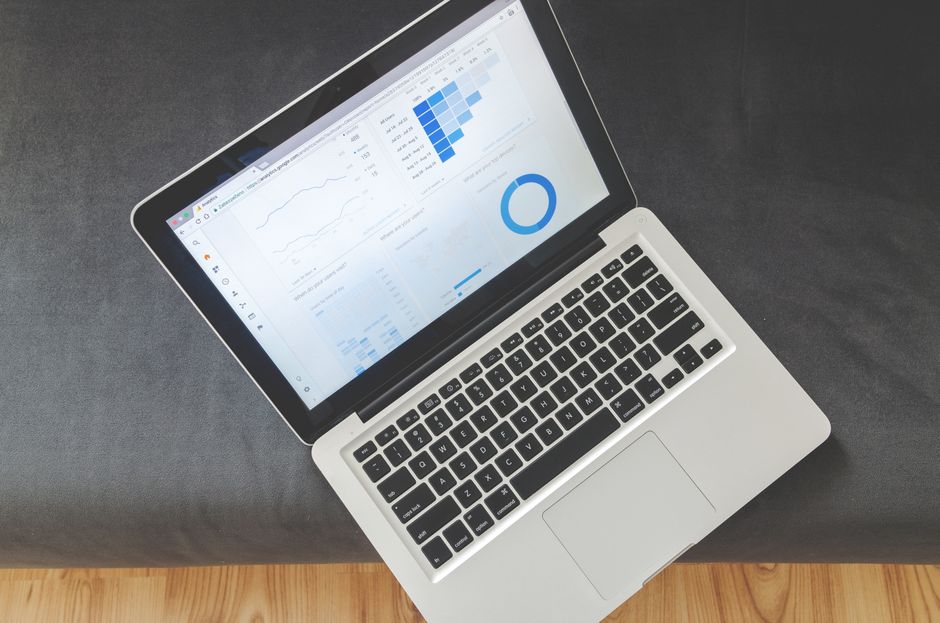 Marketing Político — Overhead view of a laptop showing data visualizations and charts on its screen.
