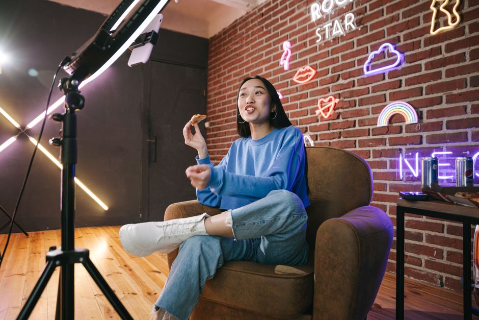 Marketing Político — Young Asian woman streaming live indoors with neon lights, engaging audience through technology and